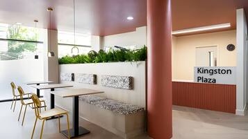 A modern interior with a seating area, a reception desk, and a sign reading 'Kingston Plaza'.