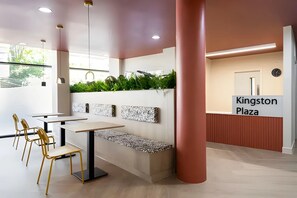 A modern interior with a seating area, a reception desk, and a sign reading 'Kingston Plaza'. - Student Only Kingston London (Kingston upon Thames)