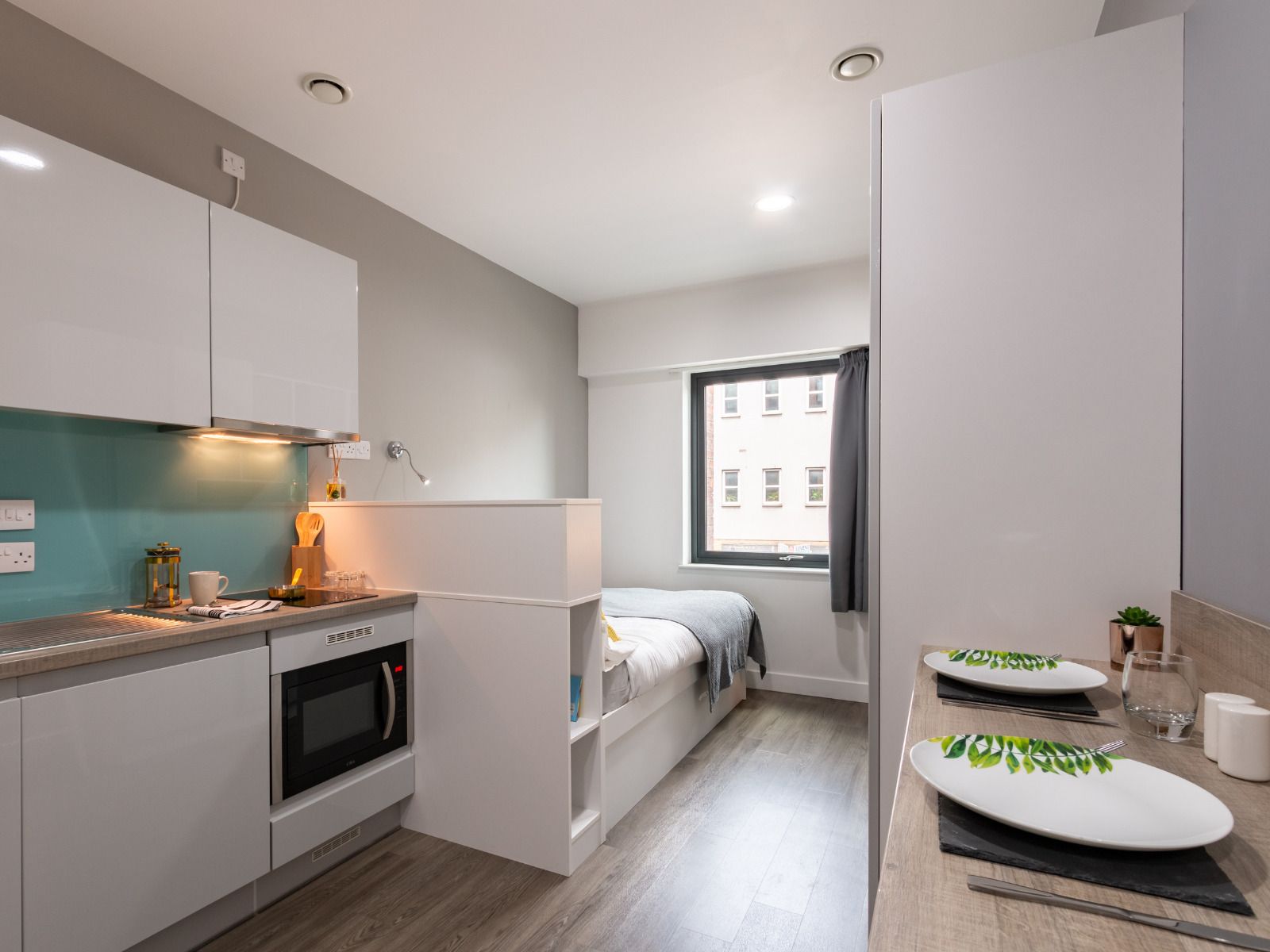 Une petite cuisine équipée d’un four à micro-ondes, d’un four et d’une petite table avec une lampe.