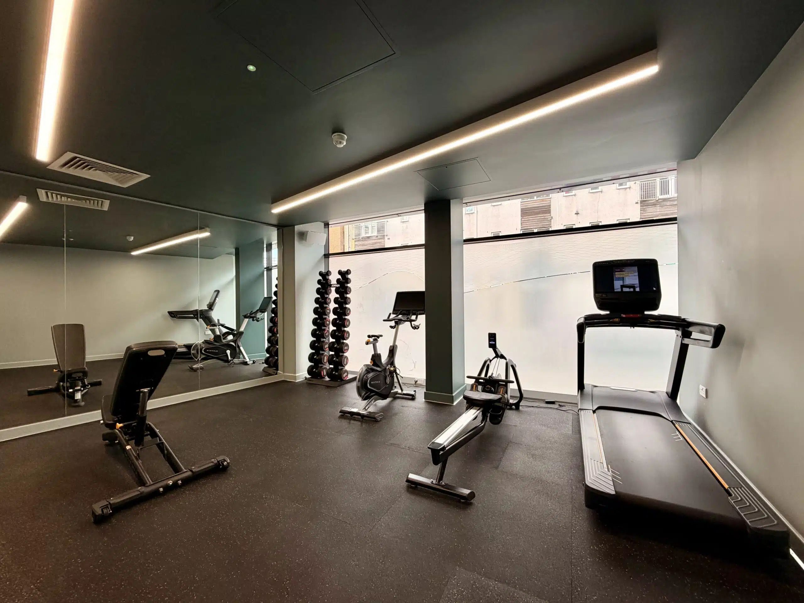 A gym with exercise equipment, a treadmill, and a mirror.