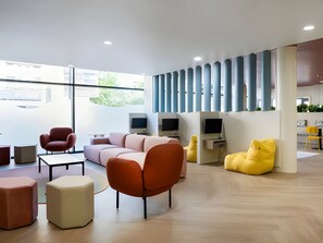 A modern interior with a sectional sofa, armchairs, a yellow bean bag, and a flat-screen TV. - Student Only Kingston London (Kingston upon Thames)