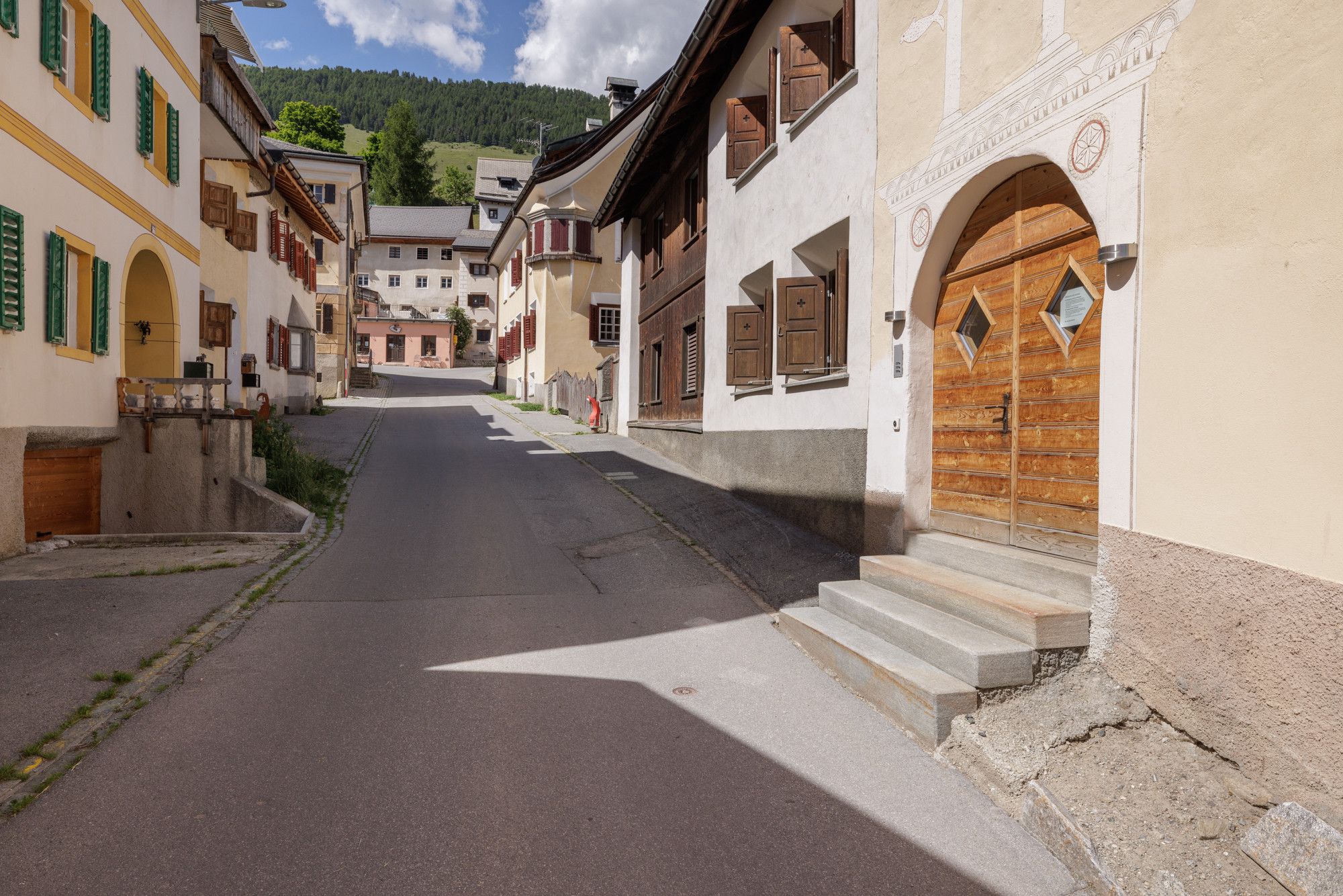 Une rue étroite bordée de bâtiments traditionnels, dotés d’entrées en arc de cercle et de volets en bois.