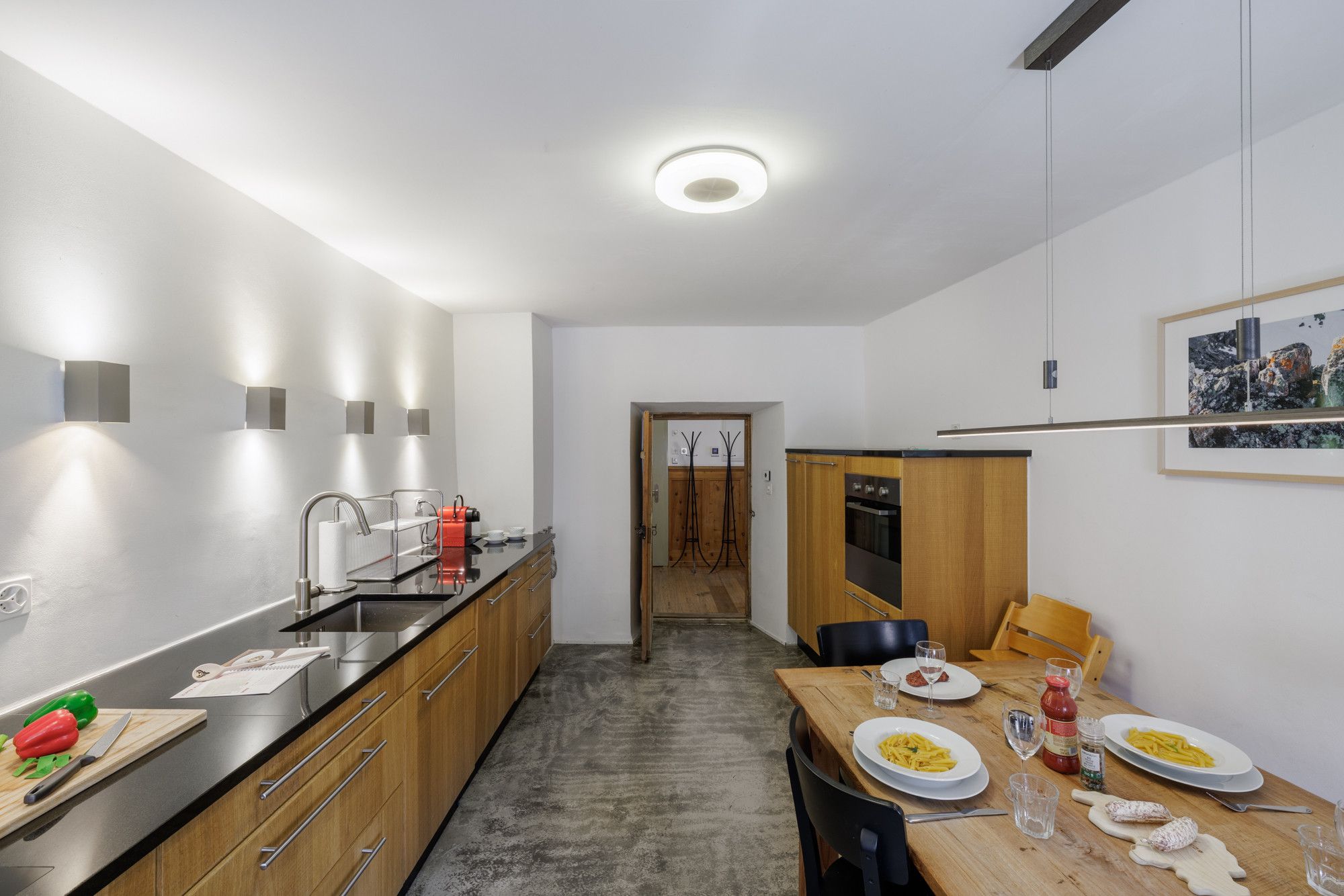 Une cuisine moderne dotée d’un îlot central, de meubles en bois et d’un coin repas avec une table dressée pour deux personnes.