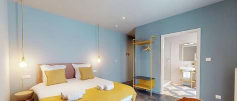 Una habitación de hotel con cama, lámparas de noche, armario y un baño visible a través de una puerta abierta.