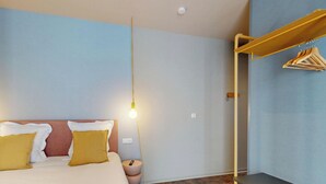 Un dormitorio moderno con una cama, lámparas de noche, una mesita de noche y un perchero.
