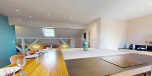 A modern hotel room with a dining area, a kitchenette, and a view of the sky. - L'Amiral 1-Bedroom Apartment - Champ d'Residence (Colmar)