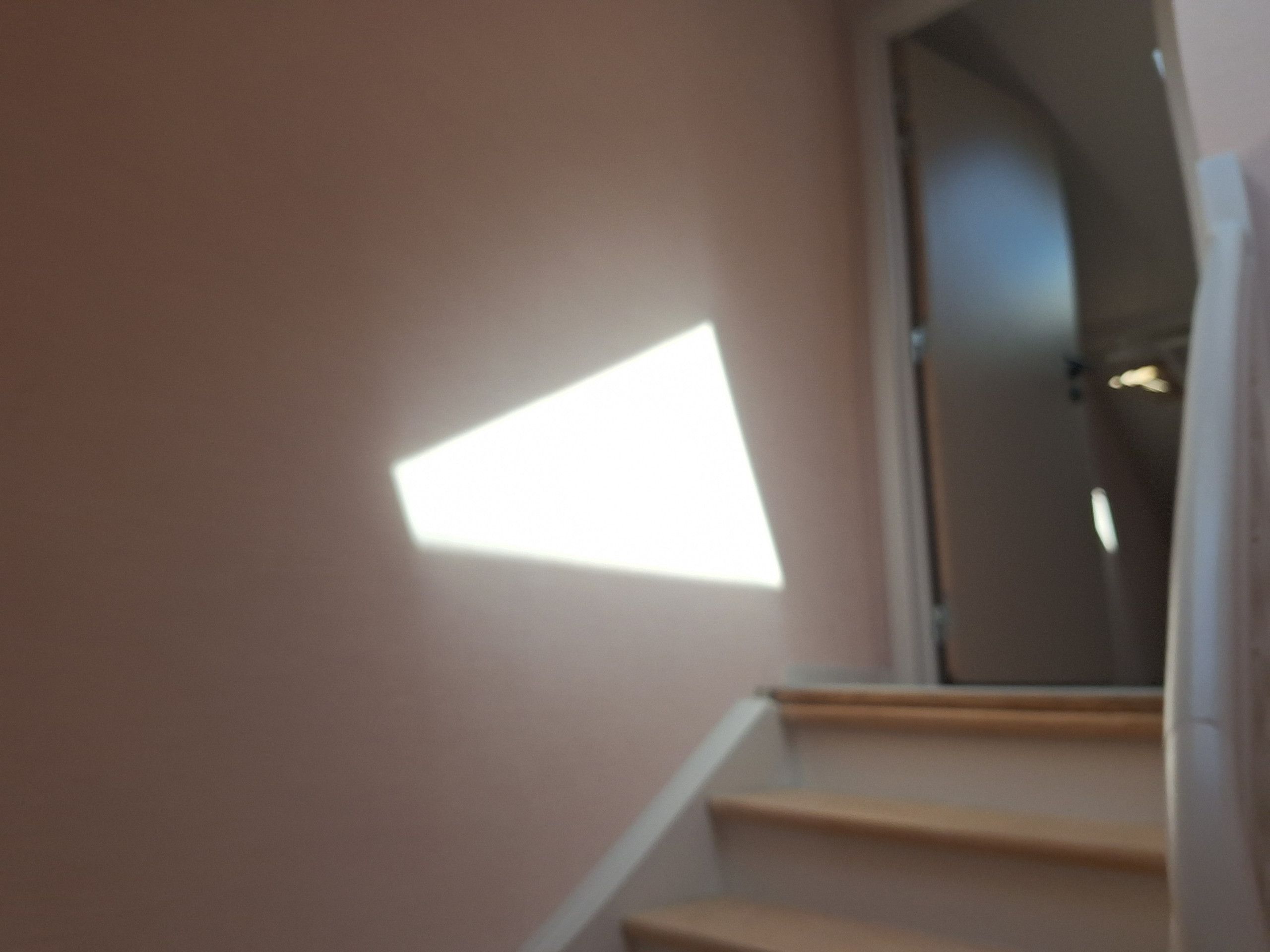 A staircase with a light fixture on the wall.