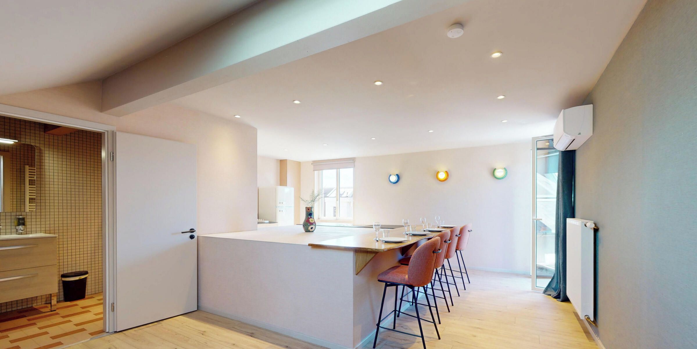A modern kitchen with a central island, bar stools, and a dining area with chairs.