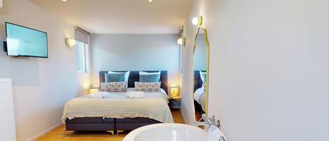 Un dormitorio moderno con una cama grande, lámparas de noche y un televisor en la pared.