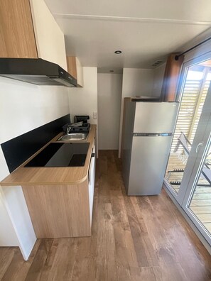 A compact kitchen with a black induction cooktop, a stainless steel refrigerator, and a wooden countertop. - Camping les Chênes Mobile Home (new) in Porto Vecchio, 50 m from the sea (Porto-Vecchio)