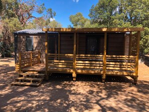 A wooden structure with a bench and a small table, surrounded by trees. - Camping les Chênes Mobile Home (new) in Porto Vecchio, 50 m from the sea (Porto-Vecchio)
