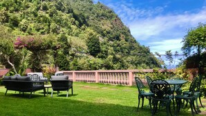 Ein Garten mit einem Tisch, Stühlen, einer Couch und einem dekorativen Zaun.