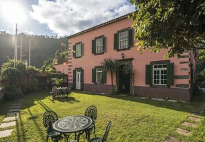 A pink building with a garden patio, a dining table, and chairs.