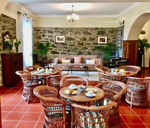 A dining area with wicker furniture and a stone wall backdrop. - Vrbo Property (Santana)