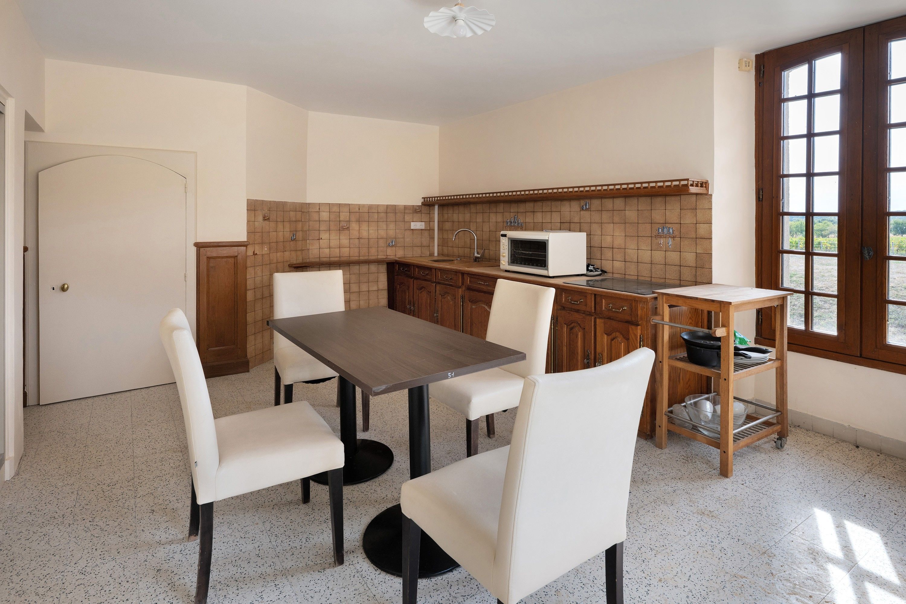 A compact kitchen with a dining table, chairs, a microwave, and a window with a view.