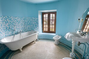 A bathroom with a clawfoot bathtub, a small bidet, and a sink with a mirror. - La Tour Gauche - Château Grange Arthuis (Lavau)