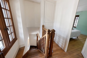 A wooden staircase with a white door at the top, leading to a room with a bed. - La Tour Gauche - Château Grange Arthuis (Lavau)