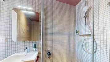 Ein Badezimmer mit einem weißen Waschbecken, einem Spiegel und einer Dusche inklusive Handbrause.
