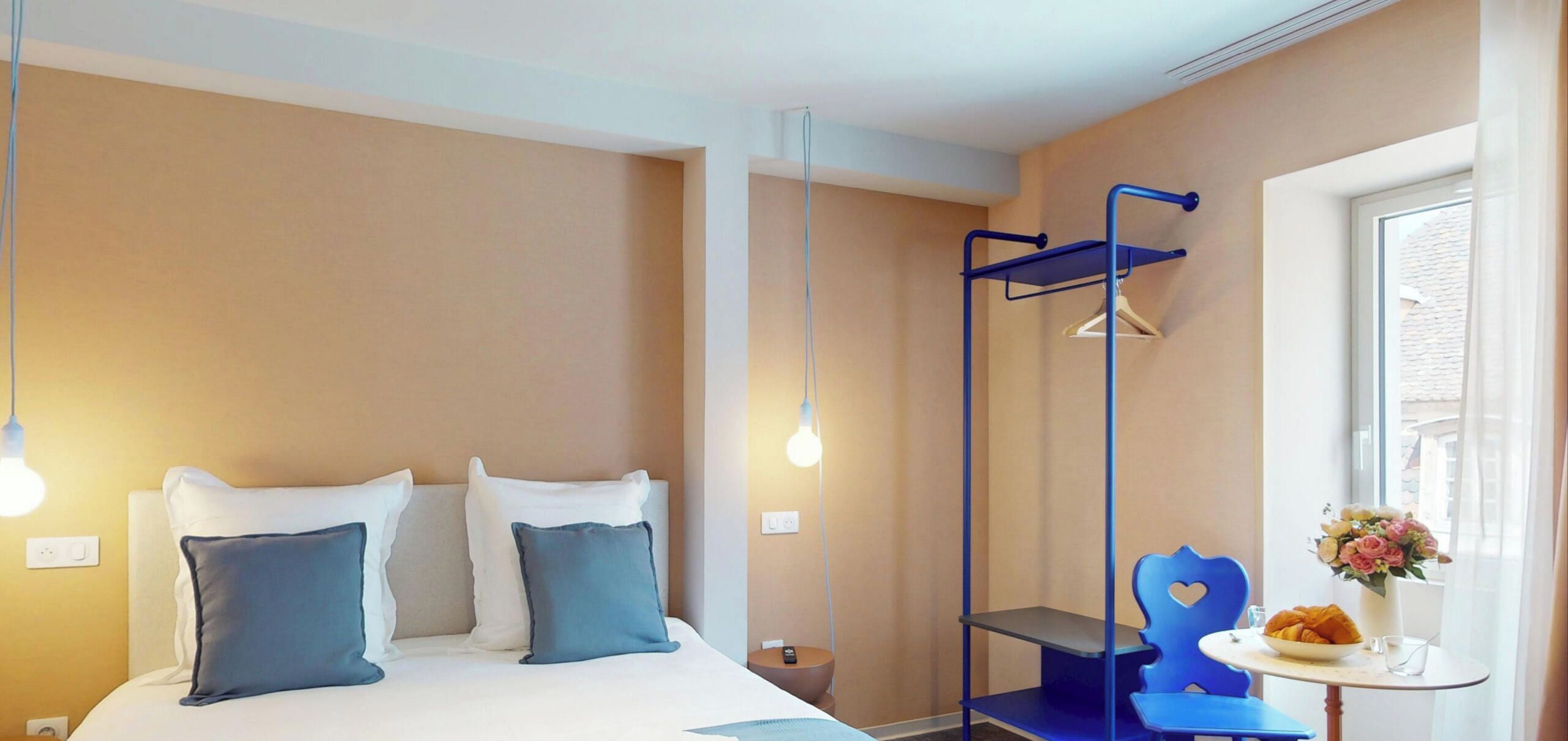 Ein Hotelzimmer mit Bett, Nachttisch, Stuhl und einem Fenster mit Blick.