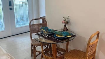 A dining area with a round glass table, wicker chairs, and a wall-mounted turtle artwork.