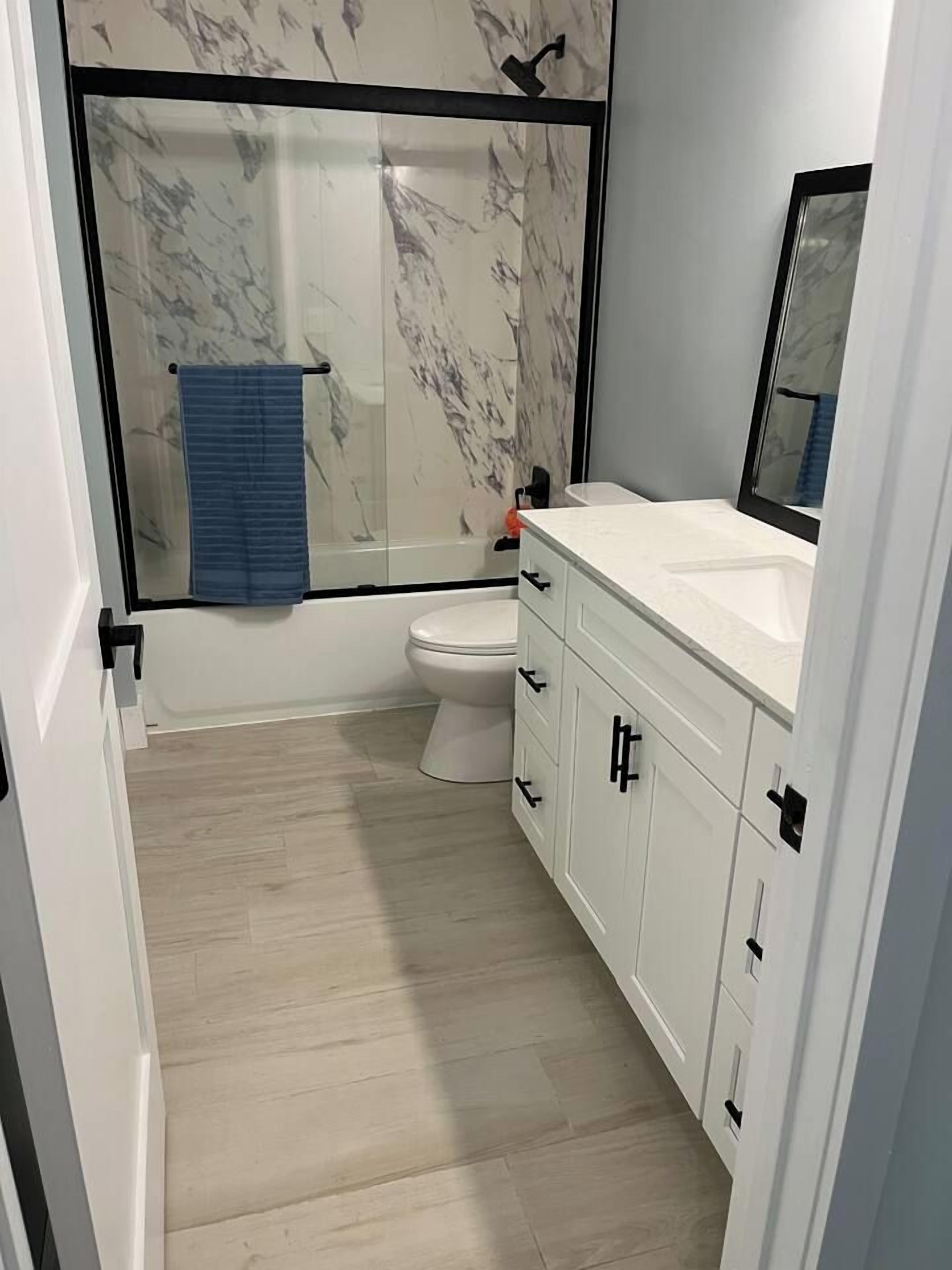 Een badkamer met douche, toilet en wastafel.
