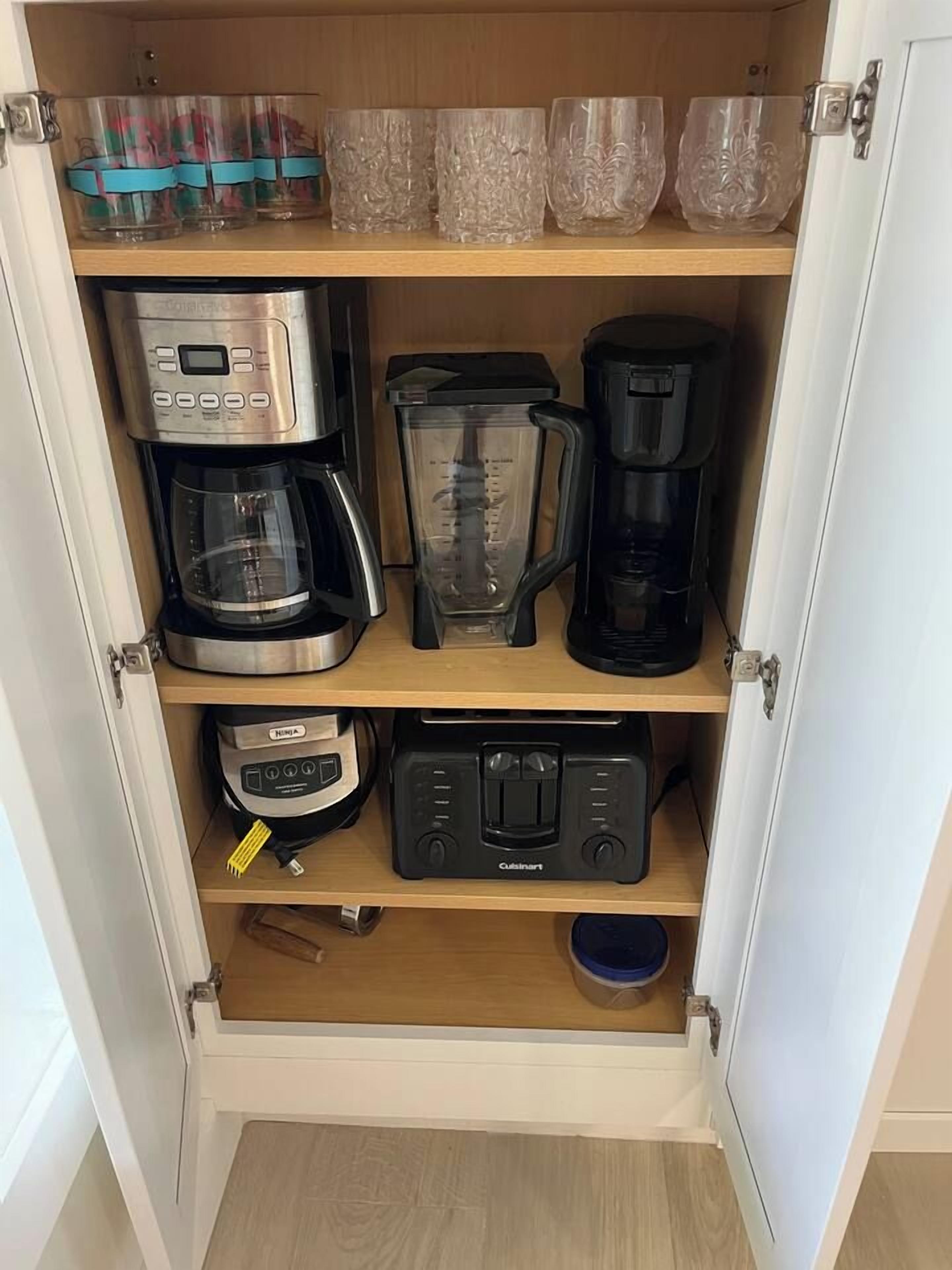 A kitchen cabinet with a coffee maker, blender, and toaster.
