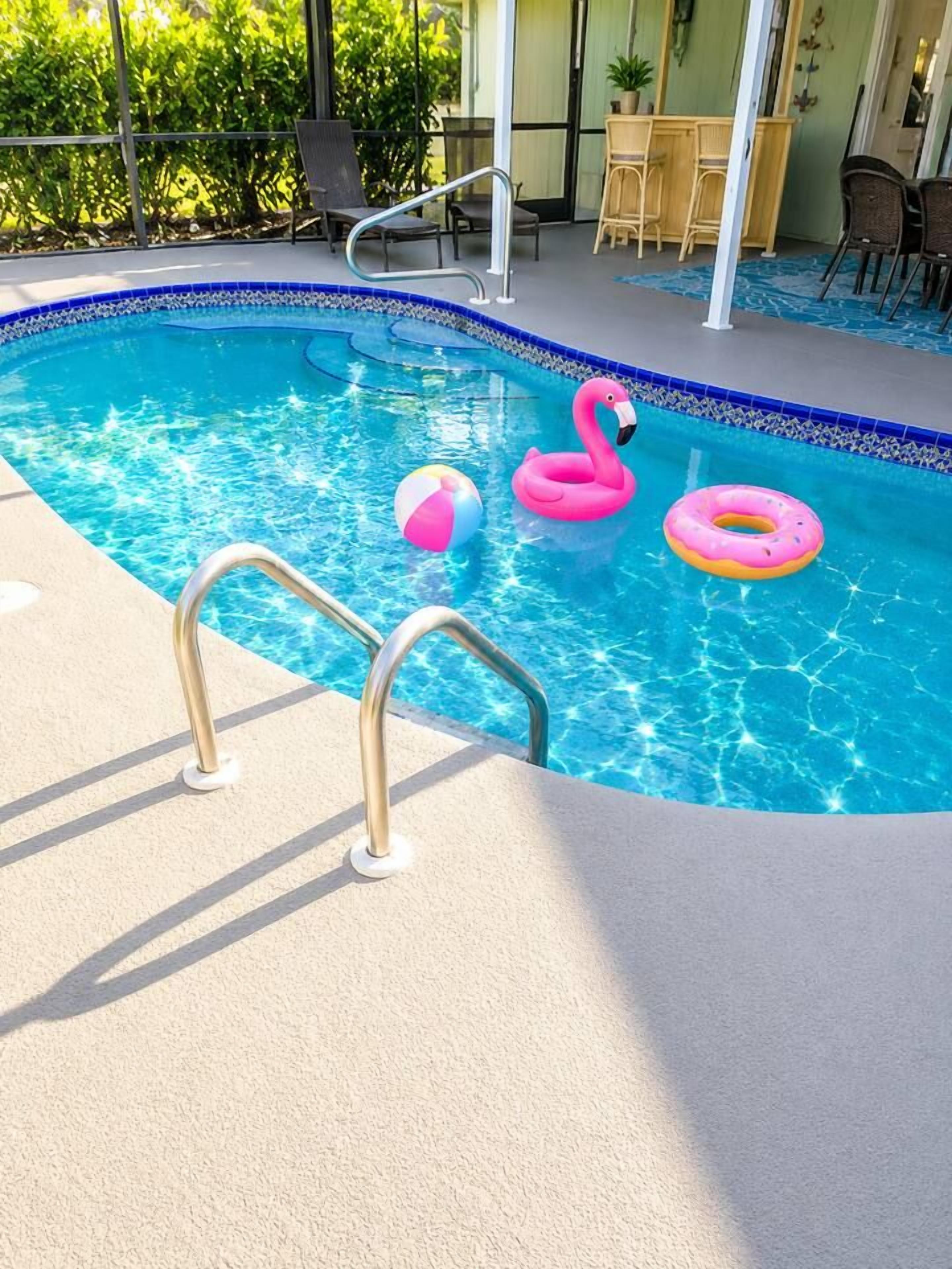 A swimming pool with a pool ladder, lounge chairs, and a table with chairs.