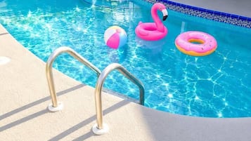 A swimming pool with a pool ladder, lounge chairs, and a table with chairs.