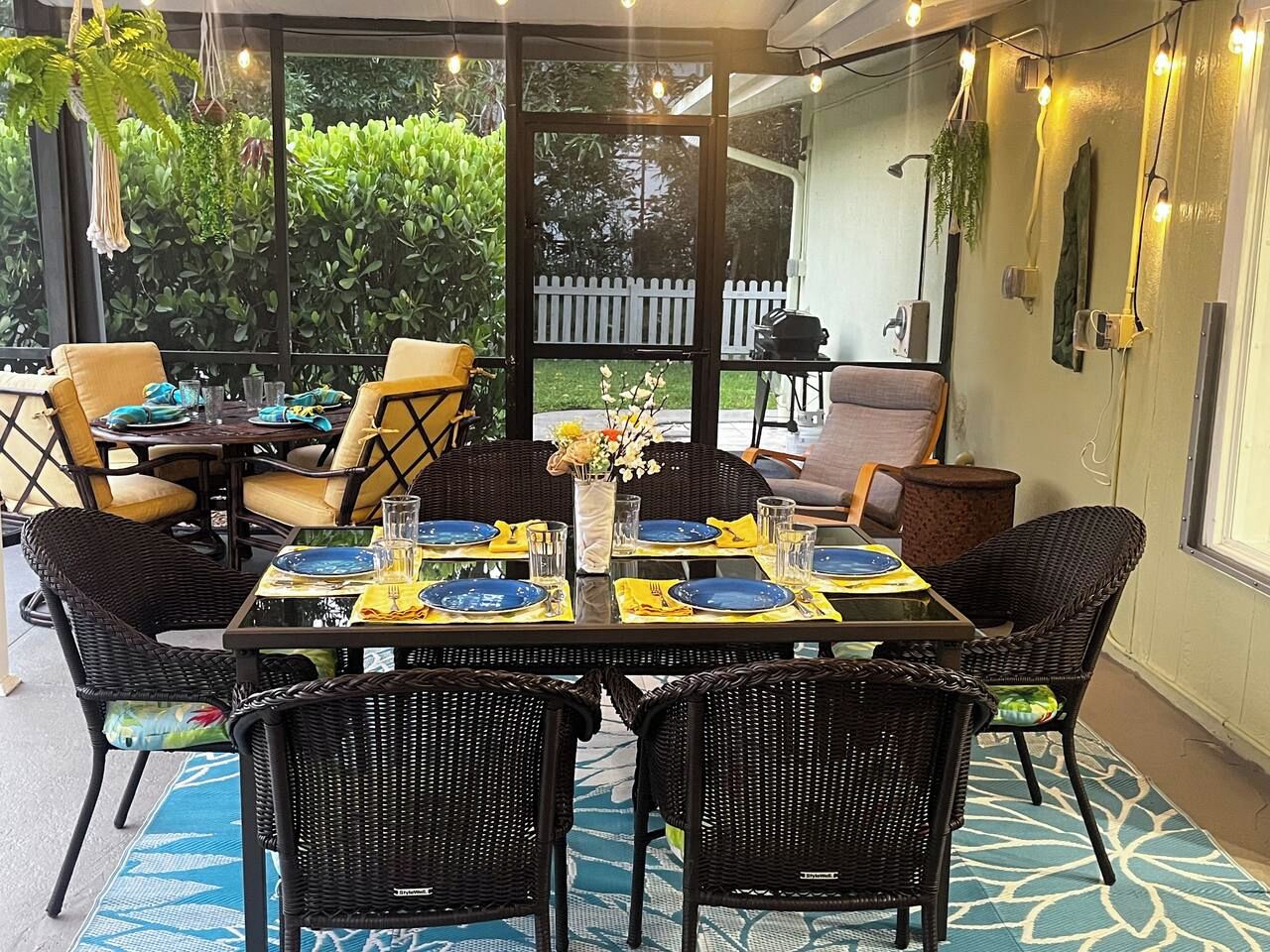 An outdoor dining area with wicker furniture, yellow napkins, and blue plates set for a meal.