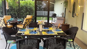 An outdoor dining area with wicker furniture, yellow napkins, and blue plates set for a meal.