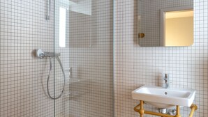 A bathroom with a glass shower enclosure, a white sink with a gold vanity, and a mirror above the sink. - Studio No. 12 - Champ de Mars Residence (Colmar)
