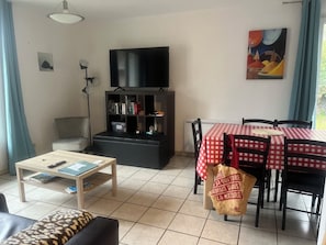 A living room with a television, bookshelf, dining table with chairs, and a sofa. - Lovely 2-bedroom house in Luz-Saint-Sauveur for a relaxing stay (Luz-Saint-Sauveur)