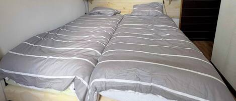 A double bed with a striped bedspread, two bedside lamps, and a wooden headboard.