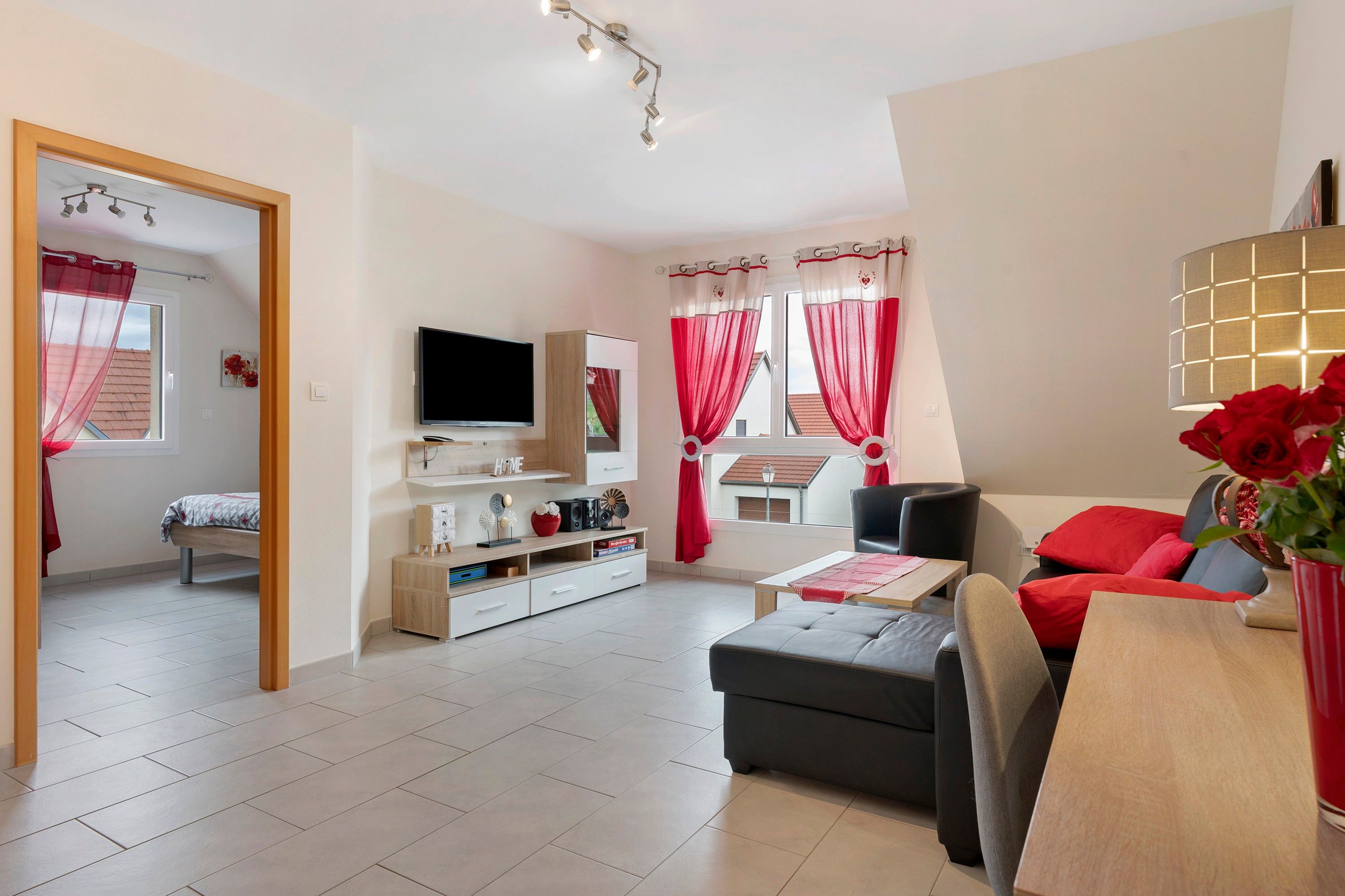 A modern living room with a flat-screen TV, a sofa, a coffee table, and a dining area.