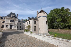 A historic building with a cobblestone courtyard and a tower. - Gite La Tour D - Chateau Grange Arthuis with Shared Garden, Wi-Fi, and Air Conditioning (Lavau)