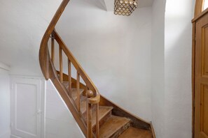 A wooden staircase with a handrail, leading to a landing with a chandelier. - Gite La Tour D - Chateau Grange Arthuis with Shared Garden, Wi-Fi, and Air Conditioning (Lavau)