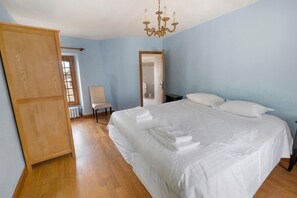 Ein Schlafzimmer mit einem großen Bett, einem Sessel, einem Kleiderschrank und einer Chandelier.