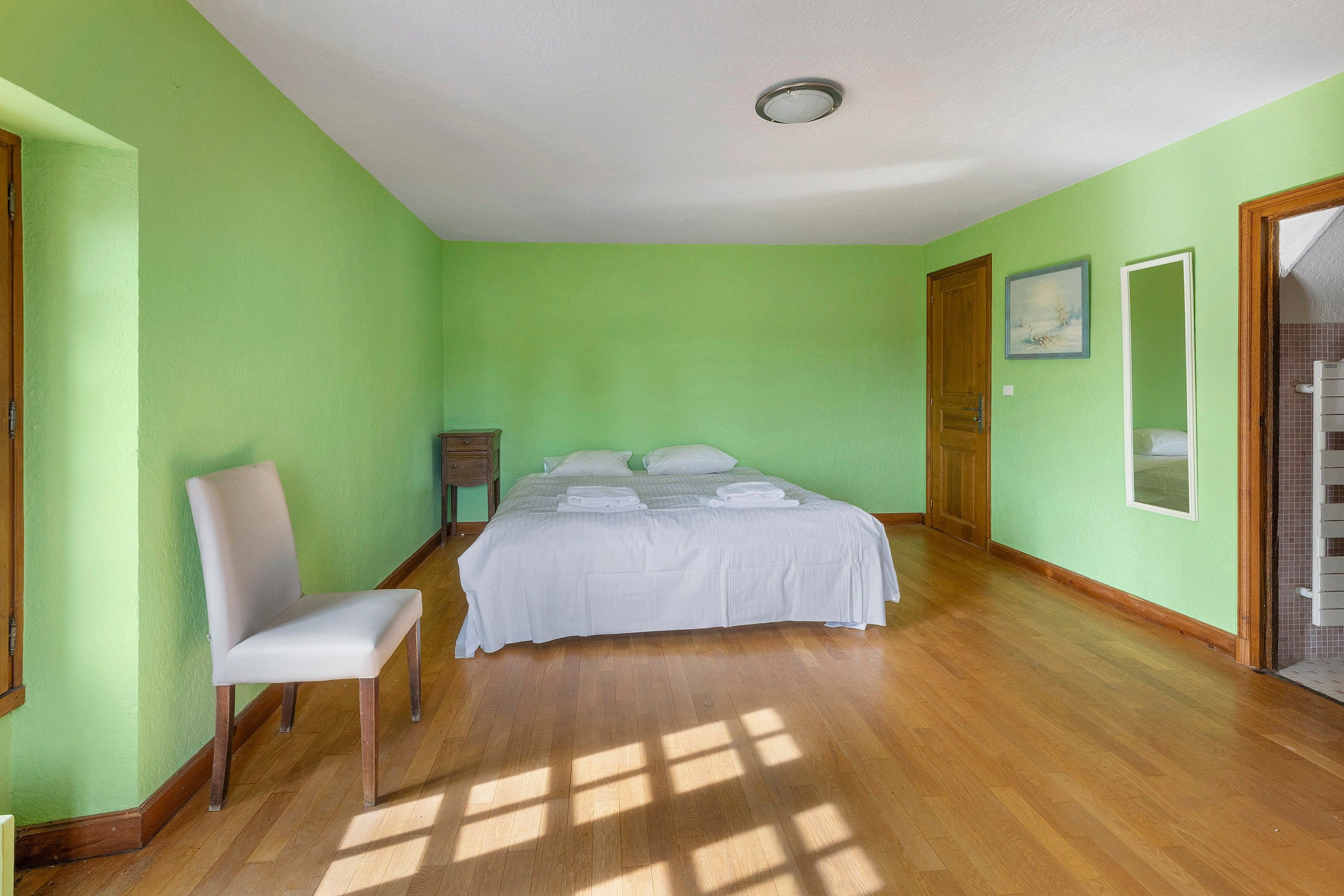 A bedroom with a bed, a chair, and a door.