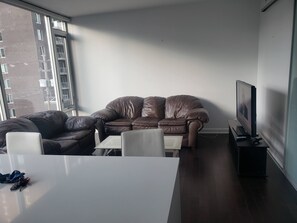 A modern living room with a brown leather sofa, a white coffee table, and a television on a stand.