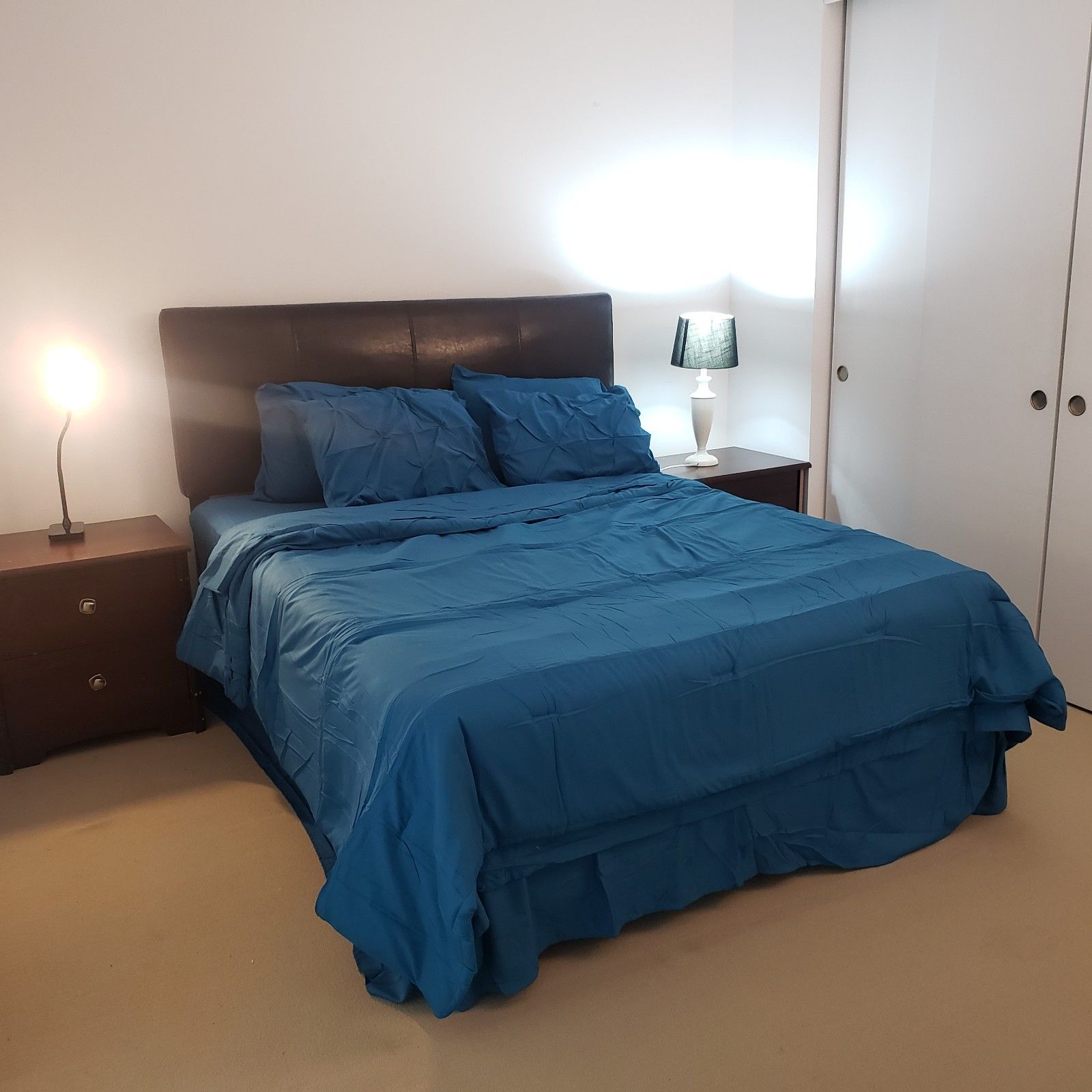 Une chambre à coucher avec un lit, une table de chevet, une lampe et une armoire.