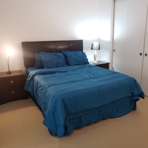 A bedroom with a bed, nightstand, lamp, and wardrobe.