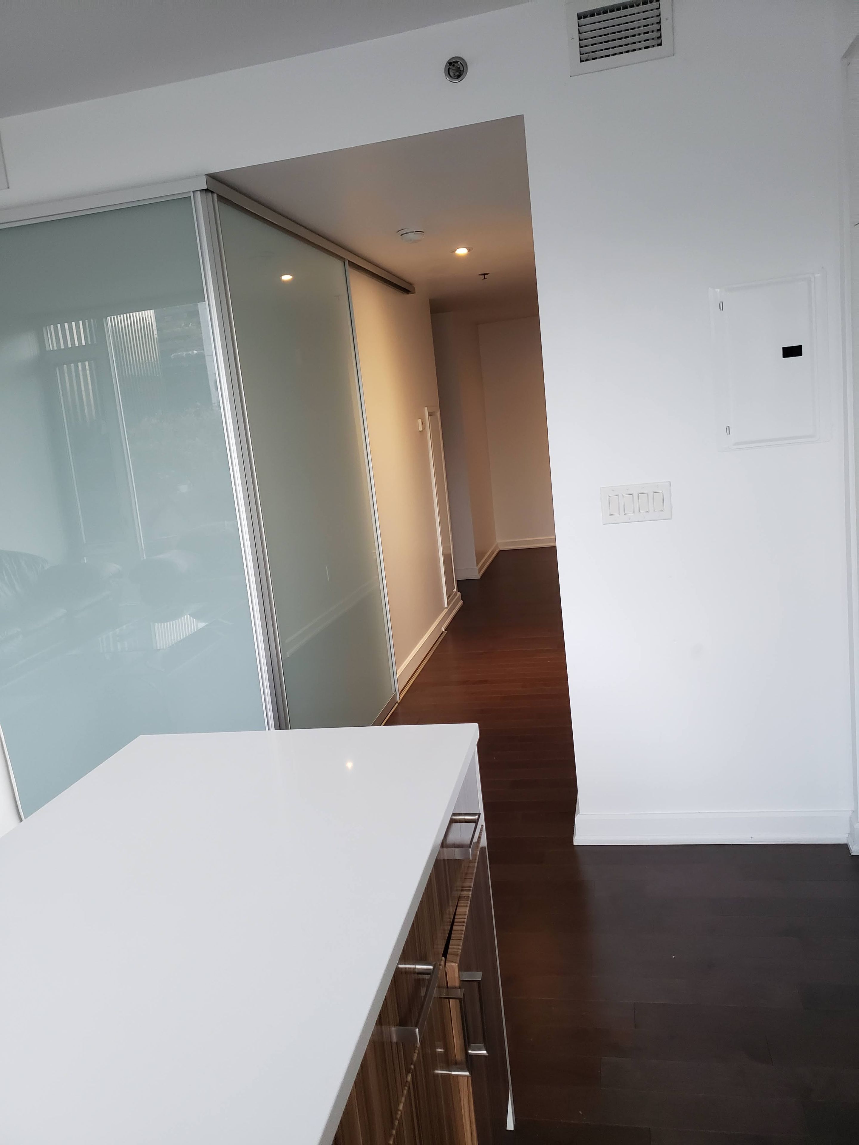 Une chambre d’hôtel moderne dotée d’une grande porte-fenêtre coulissante, d’un plancher en bois et d’un mur blanc avec un interrupteur.