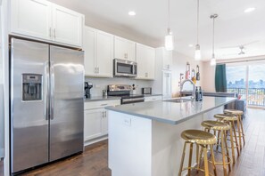 A modern kitchen with stainless steel appliances, white cabinetry, and a large island with bar stools. - The Fern & Fiddle by Stay Local Nashville - Skyline Views & Games Near Downtown (Nashville)