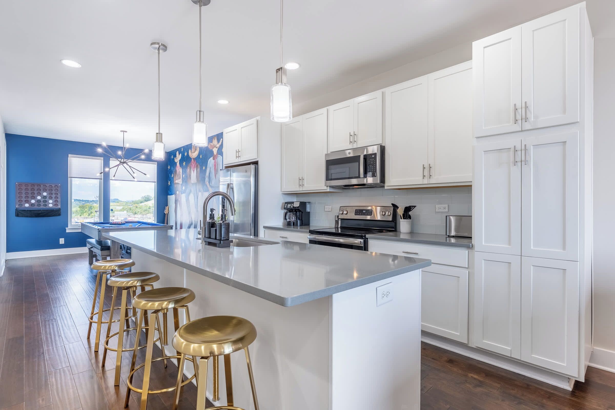 Een moderne keuken met witte kasten, roestvrijstalen apparatuur en een centraal eiland met barkrukken.