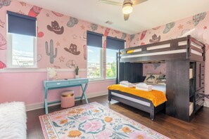 A bedroom with a bunk bed, a desk, a chair, a small potted plant, and a floral rug. - The Fern & Fiddle by Stay Local Nashville - Skyline Views & Games Near Downtown (Nashville)