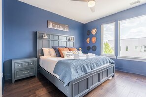 Ein Schlafzimmer mit einem Bett, Nachttischen, einem Deckenventilator und Stadtbild-Wandkunst.