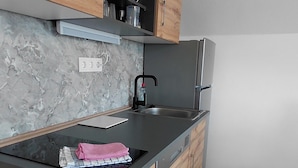 A modern kitchen with a marble backsplash, wooden cabinets, a stainless steel sink, and a black countertop.