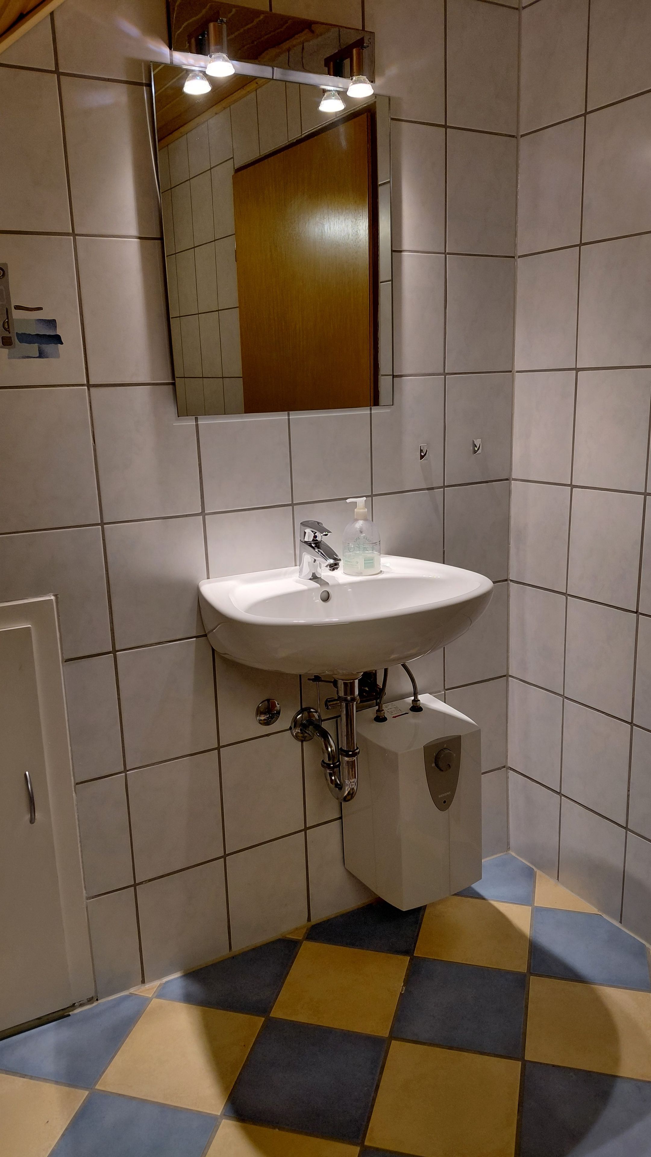 Ein Badezimmer mit einem weißen Waschbecken, einem Spiegel und einem gefliesten Boden.