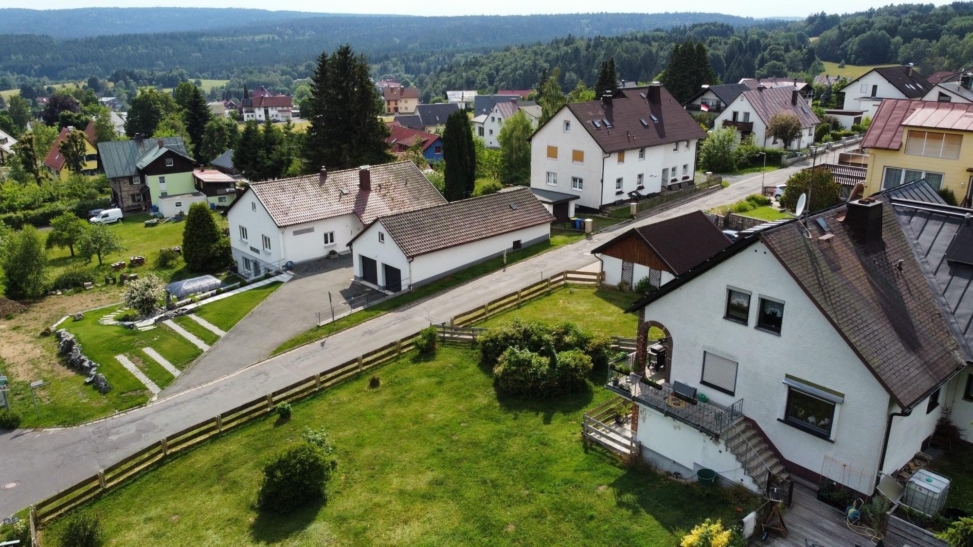 Ein Wohngebiet mit Häusern, einer asphaltierten Straße und einer Rasenfläche.