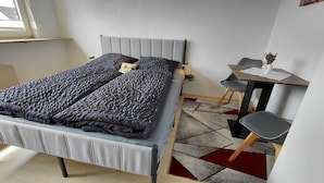 A modern bedroom with a bed, bedside table, and a small desk with a chair.